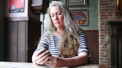 Nicola Brookes checks her mobile device for messages. She has dealt with online harassment for five years and is still fighting to have her trolls prosecuted for their alleged crimes. (Lucas Metz/CBC)